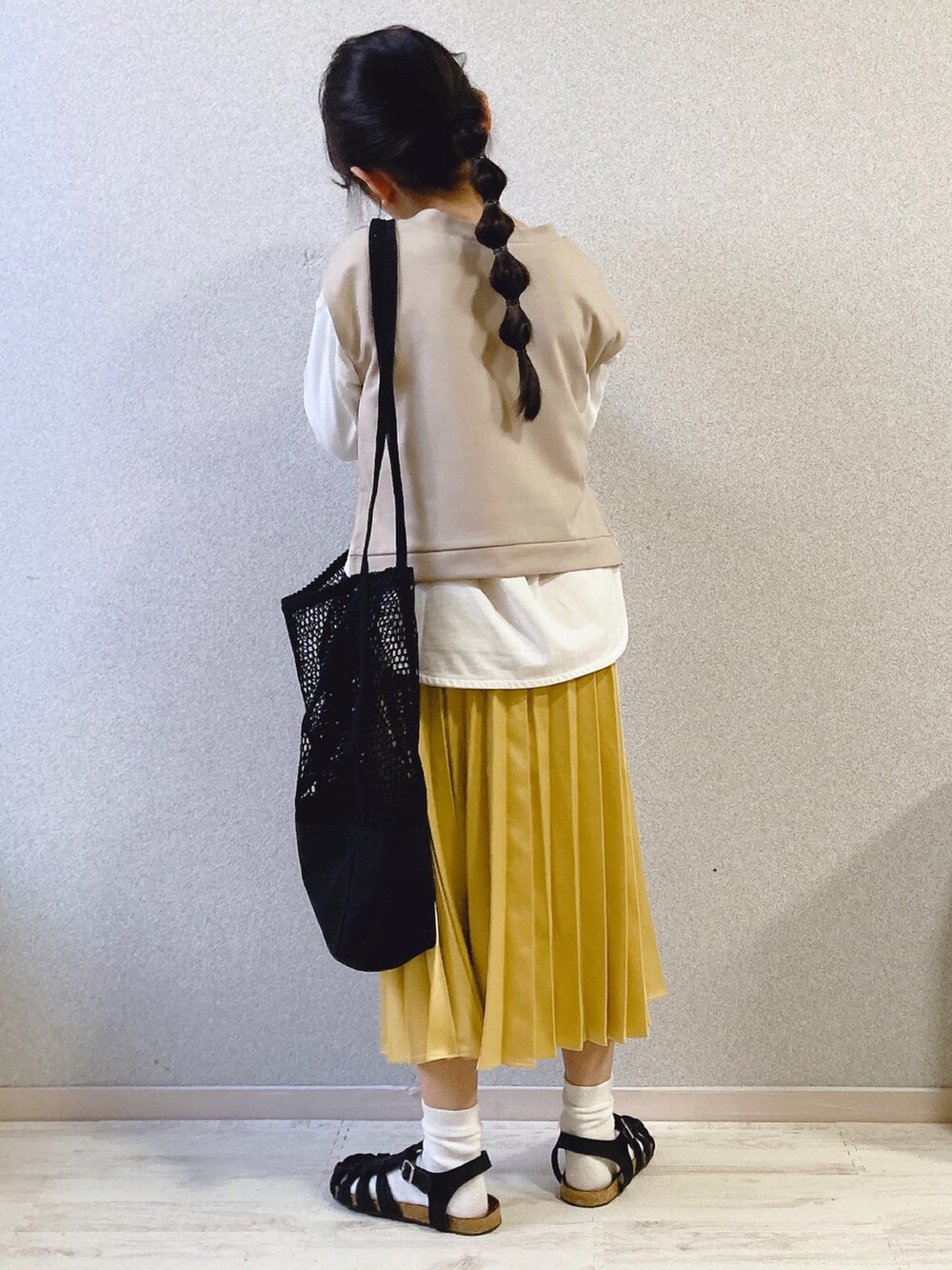 ホワイト系のTシャツ/カットソー、ベージュ系のベスト、イエロー系のスカートを着用したキッズの春コーディネートの5枚目の写真
