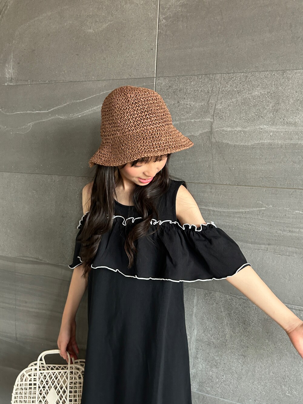 ブラック系のワンピース、オレンジ系のサンダル、ブラウン系のハットを着用したキッズの夏コーディネートの5枚目の写真