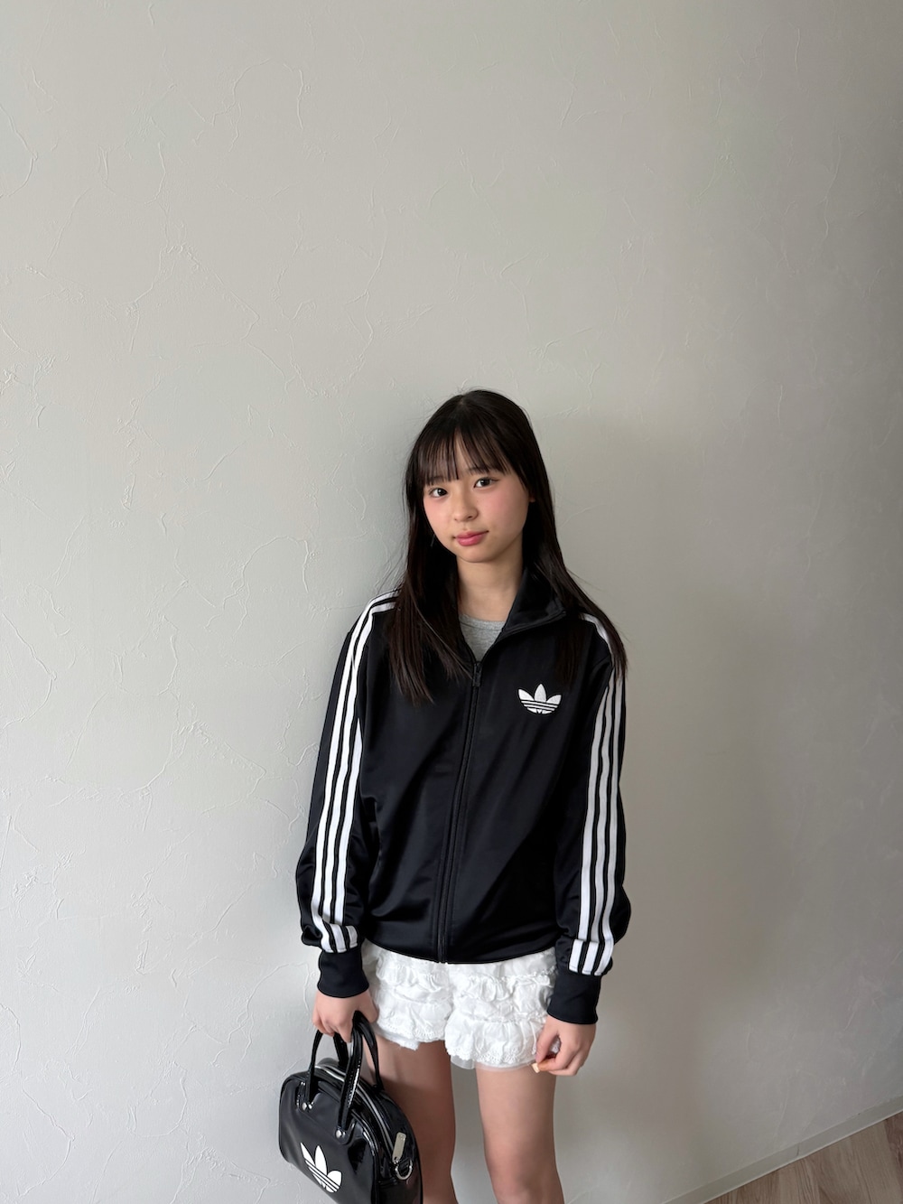 ブラック系のジャージ、ブラック系のショルダーバッグ、ブラック系のスニーカーを着用したキッズの春コーディネートの3枚目の写真