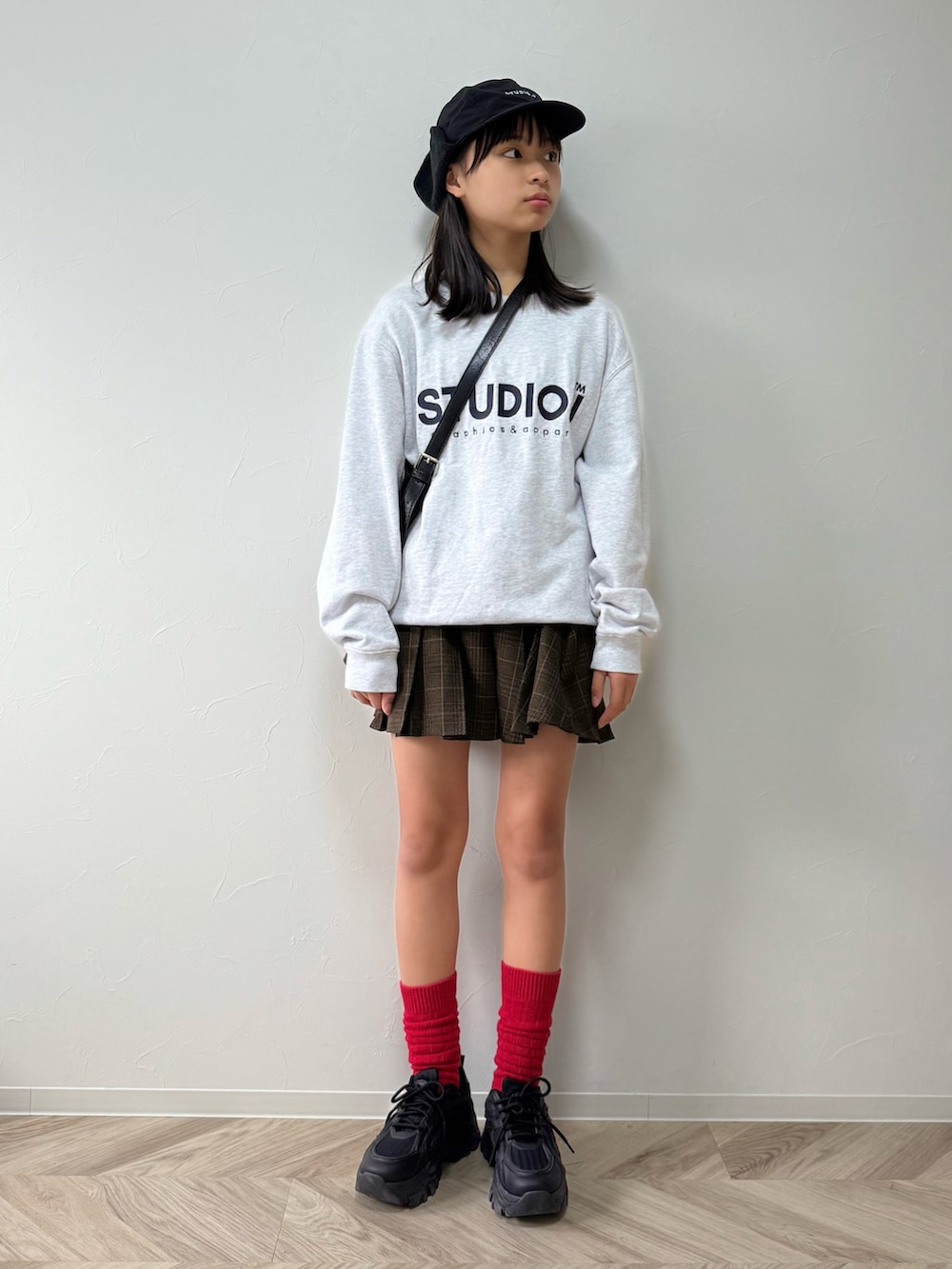 ブラック系のスニーカー、ブラウン系のスカート、ブラック系のショルダーバッグを着用したキッズの秋コーディネートの2枚目の写真