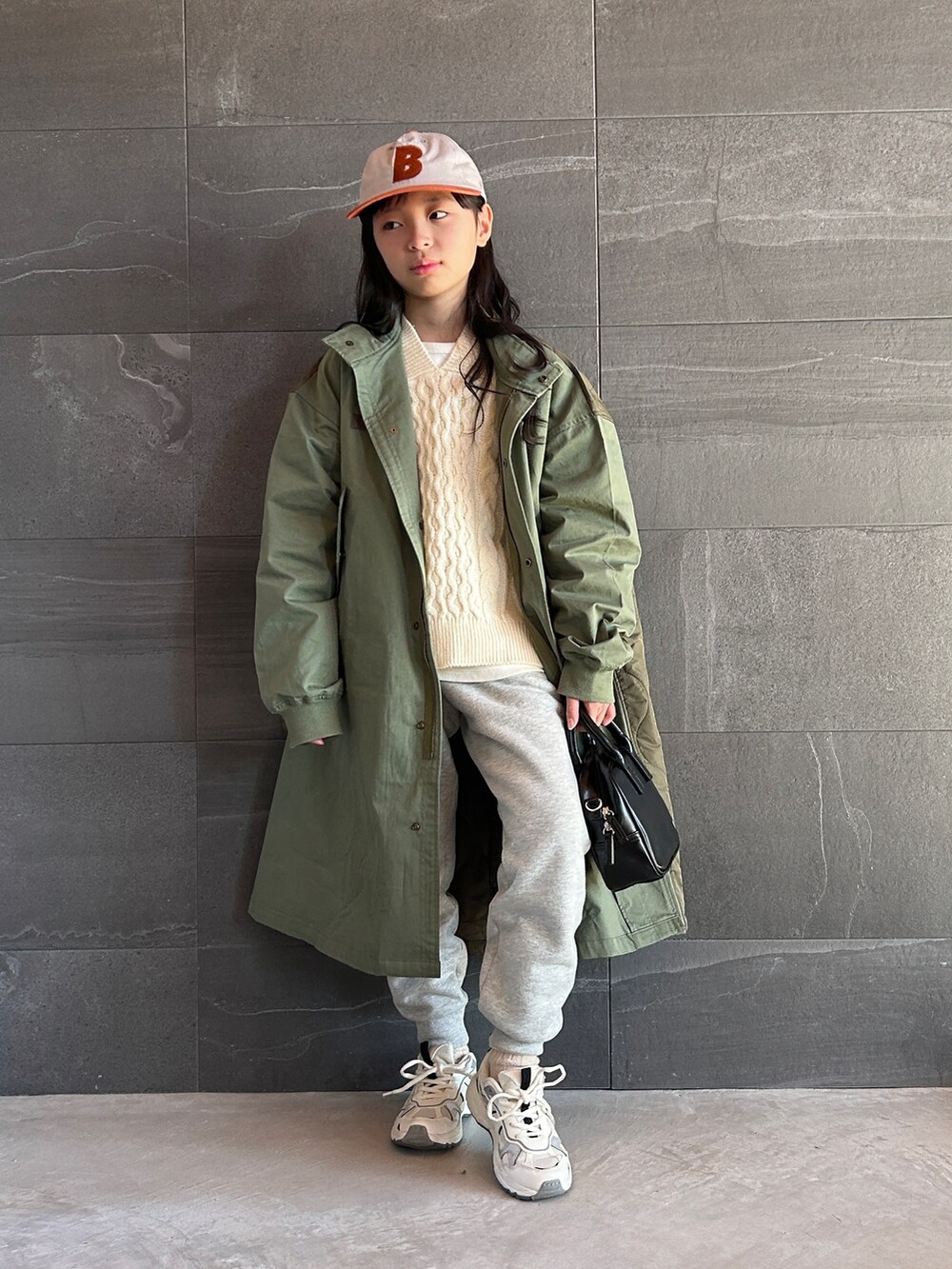 グリーン系のモッズコート、ベージュ系のニット/セーター、ホワイト系のTシャツ/カットソーを着用したキッズの冬コーディネートの5枚目の写真