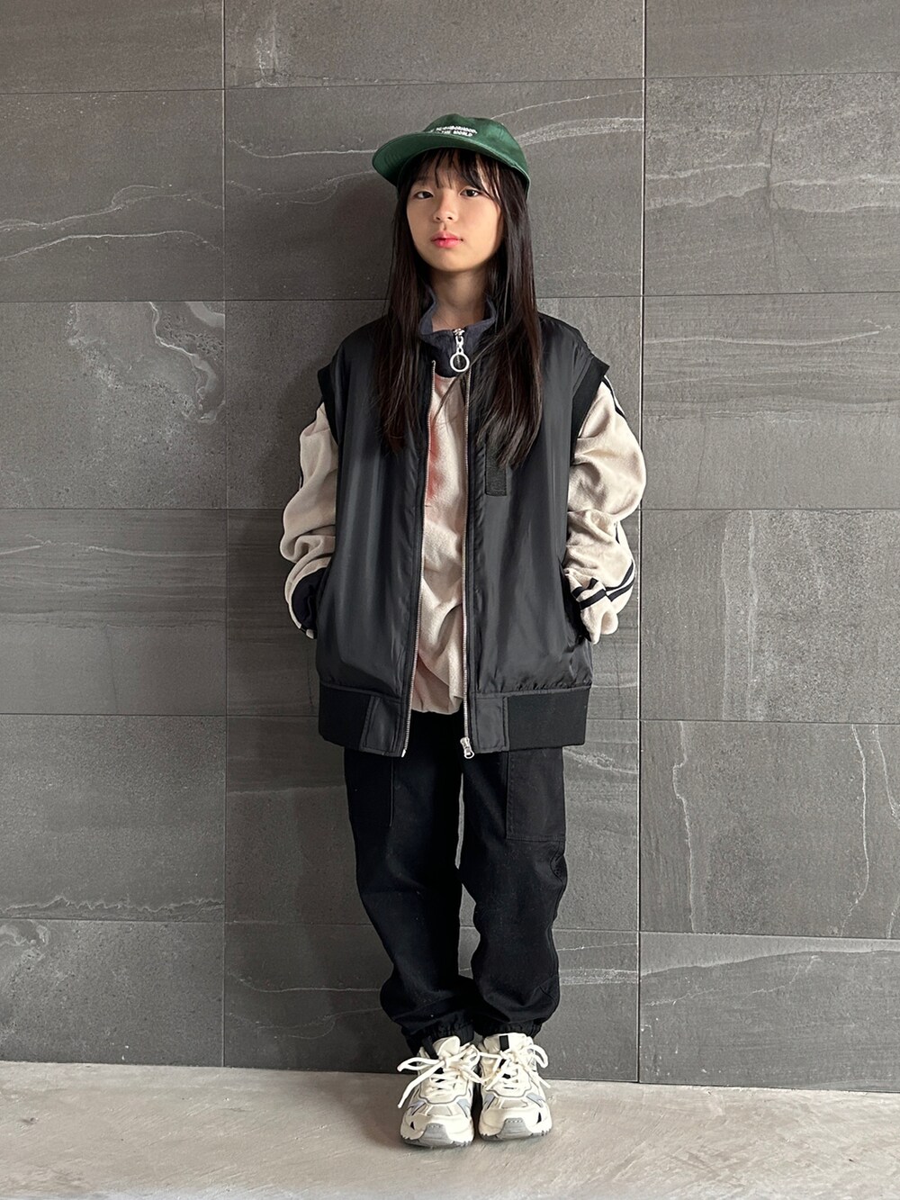 ブラック系のダウンベスト、グレー系のスウェット、ホワイト系のカーゴパンツを着用したキッズの秋コーディネートの3枚目の写真