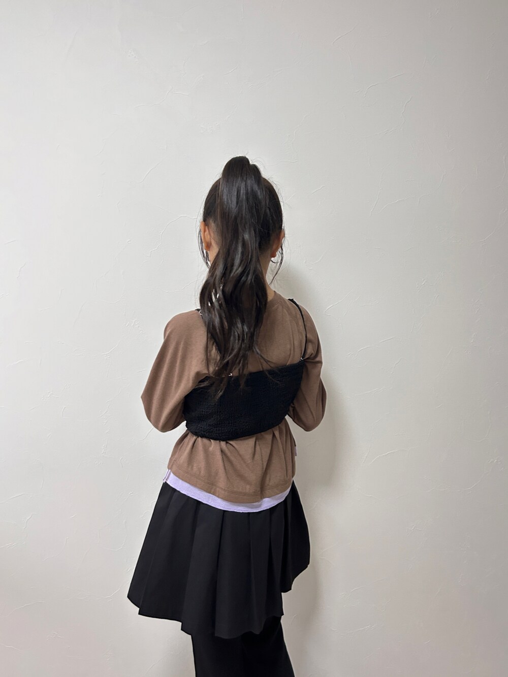 ブラウン系のTシャツ/カットソー、ブラック系のスカート、ベージュ系のスニーカーを着用したキッズの秋コーディネートの4枚目の写真