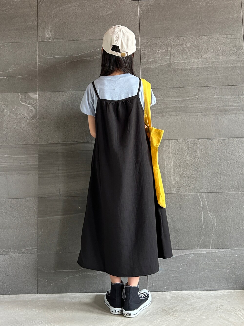 ブラック系のワンピース、イエロー系のトートバッグ、ブラック系のスニーカーを着用したキッズの夏コーディネートの3枚目の写真