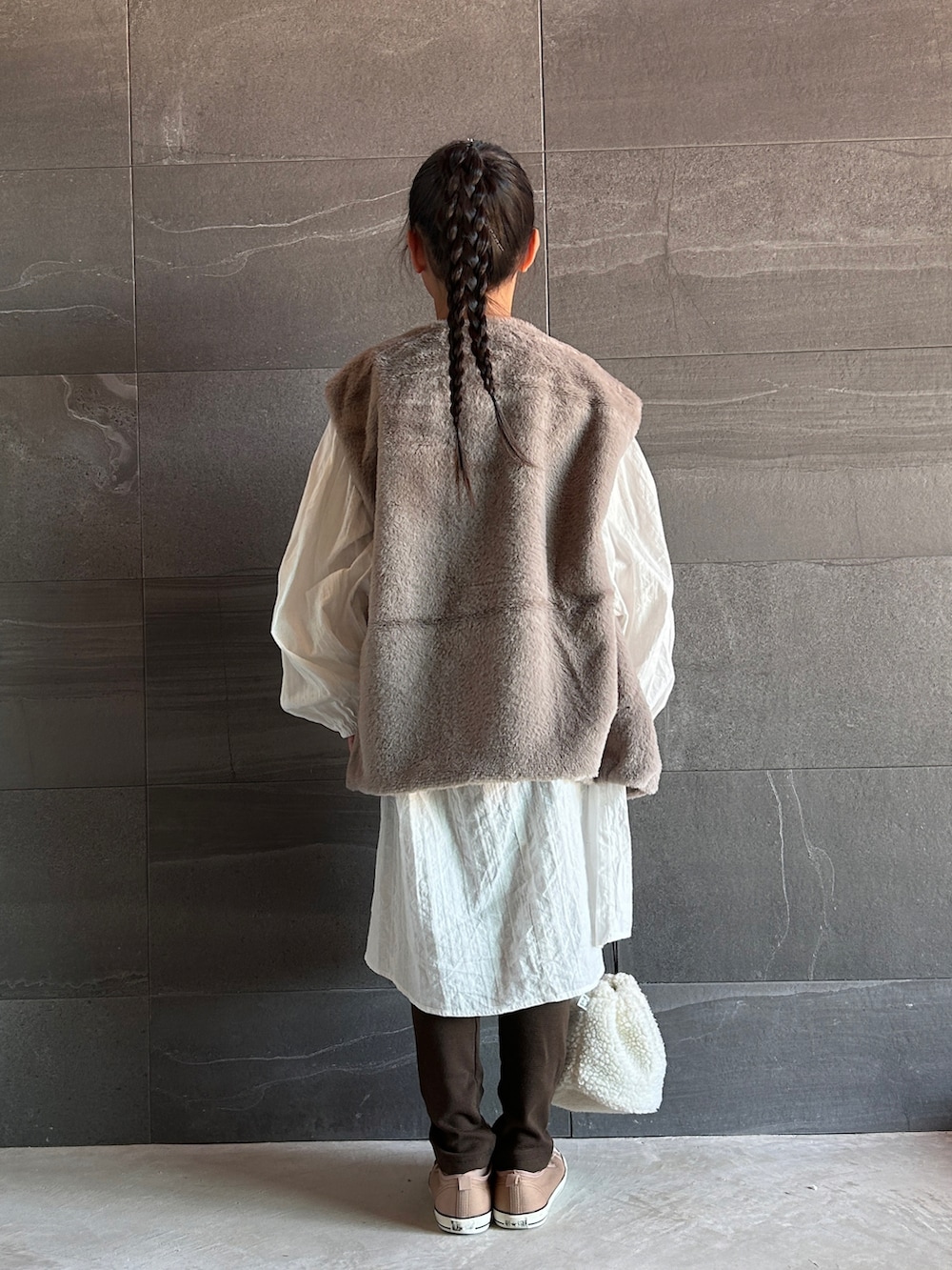 グレー系のベスト、ブラウン系のスウェットパンツ、ホワイト系のワンピースを着用したキッズの秋コーディネートの2枚目の写真