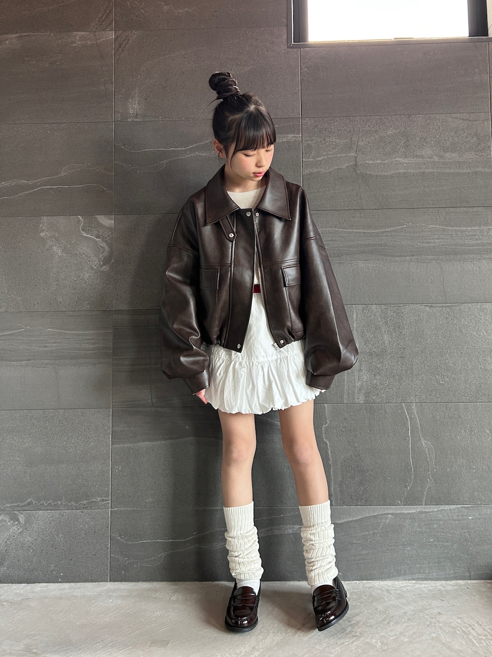 ブラウン系のブルゾン、ホワイト系のスカート、ベージュ系のTシャツ/カットソーを着用したキッズの冬コーディネートの2枚目の写真