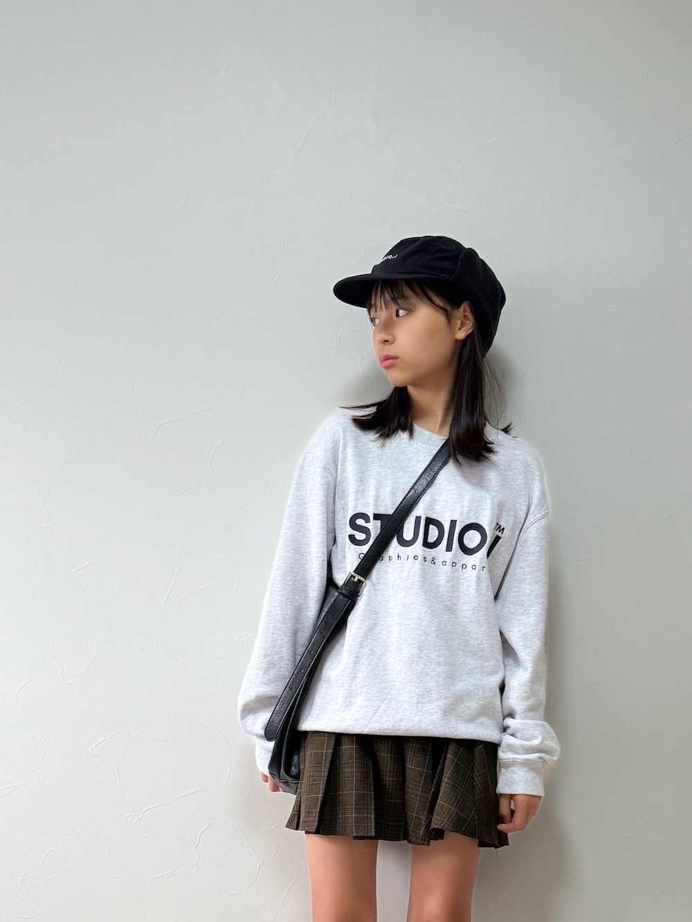 ブラック系のスニーカー、ブラウン系のスカート、ブラック系のショルダーバッグを着用したキッズの秋コーディネートの3枚目の写真