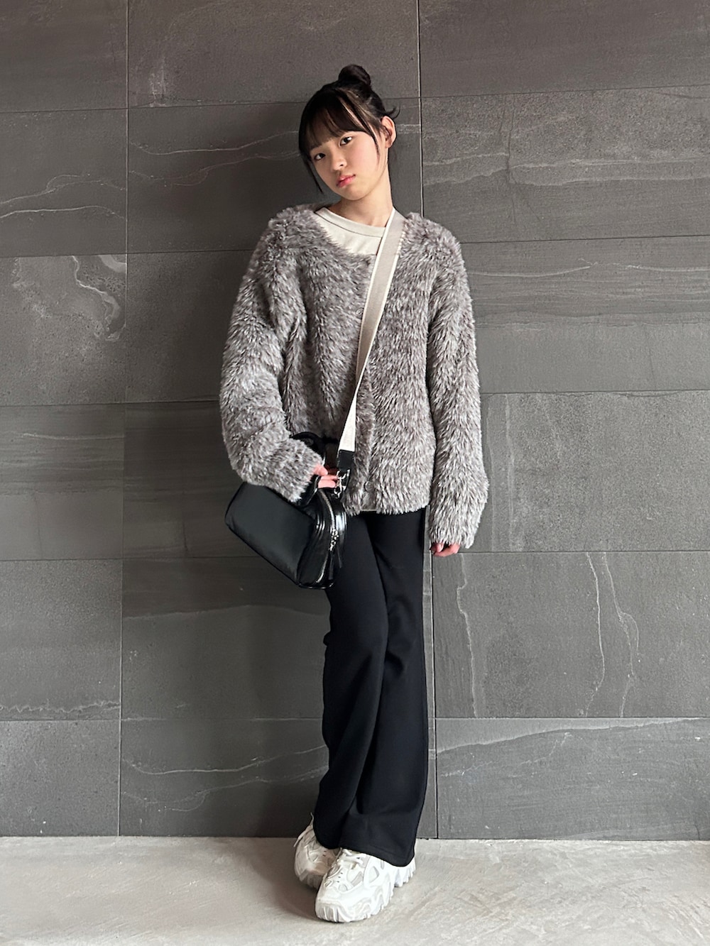 ブラウン系のカーディガン/ボレロ、ベージュ系のTシャツ/カットソー、ブラック系のショルダーバッグを着用したキッズの冬コーディネートの4枚目の写真