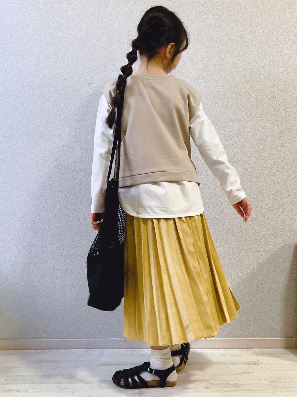 ホワイト系のTシャツ/カットソー、ベージュ系のベスト、イエロー系のスカートを着用したキッズの春コーディネートの4枚目の写真