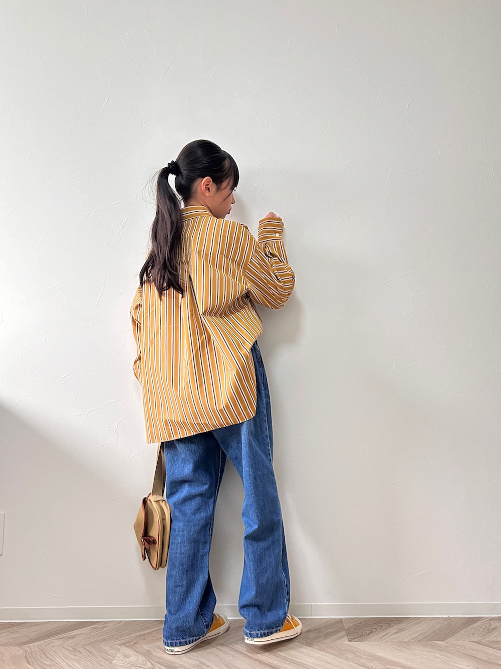 イエロー系のシャツ/ブラウス、ブルー系のデニムパンツ、ベージュ系のショルダーバッグを着用したキッズの秋コーディネートの2枚目の写真