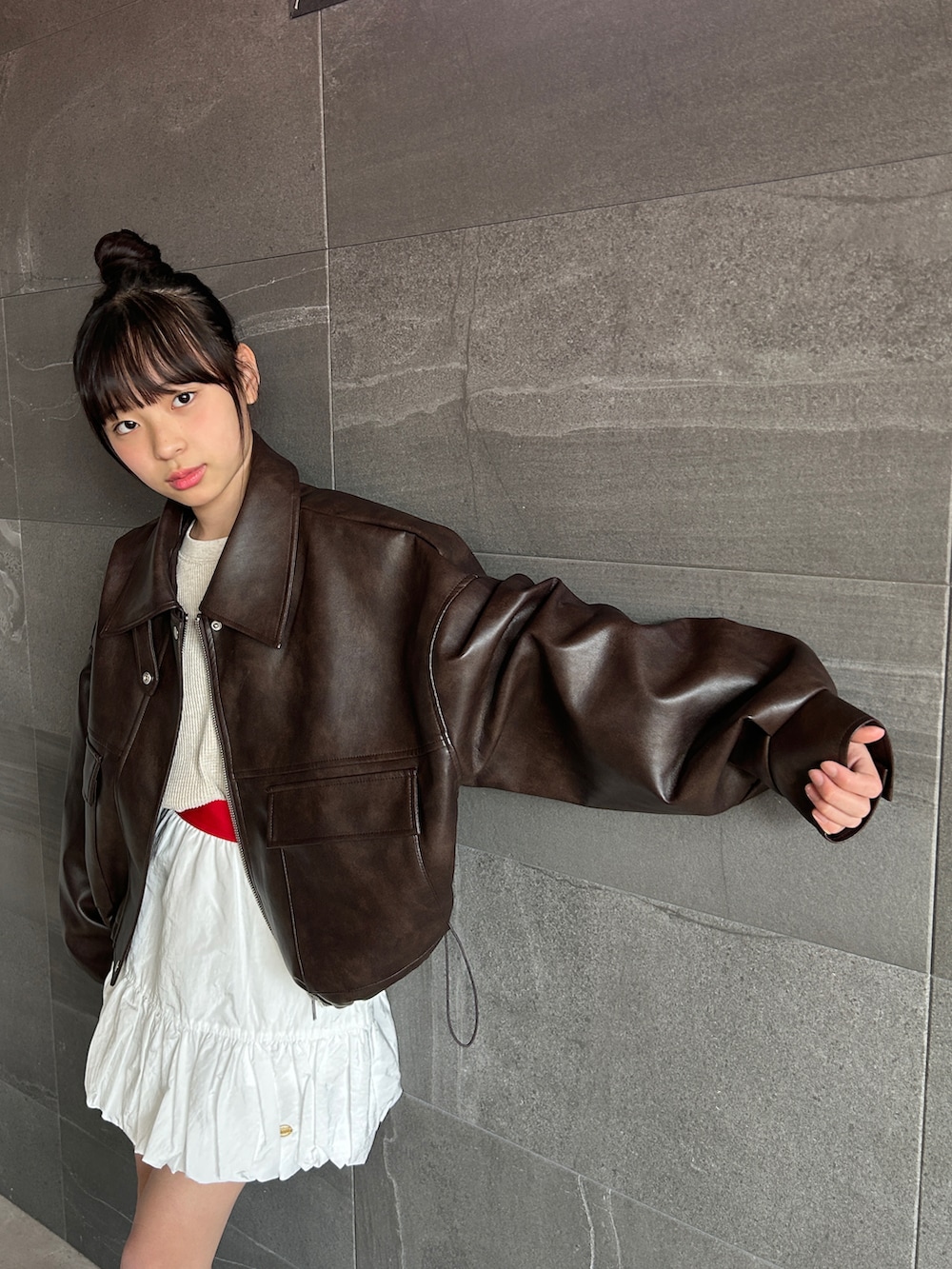 ブラウン系のブルゾン、ホワイト系のスカート、ベージュ系のTシャツ/カットソーを着用したキッズの冬コーディネートの5枚目の写真