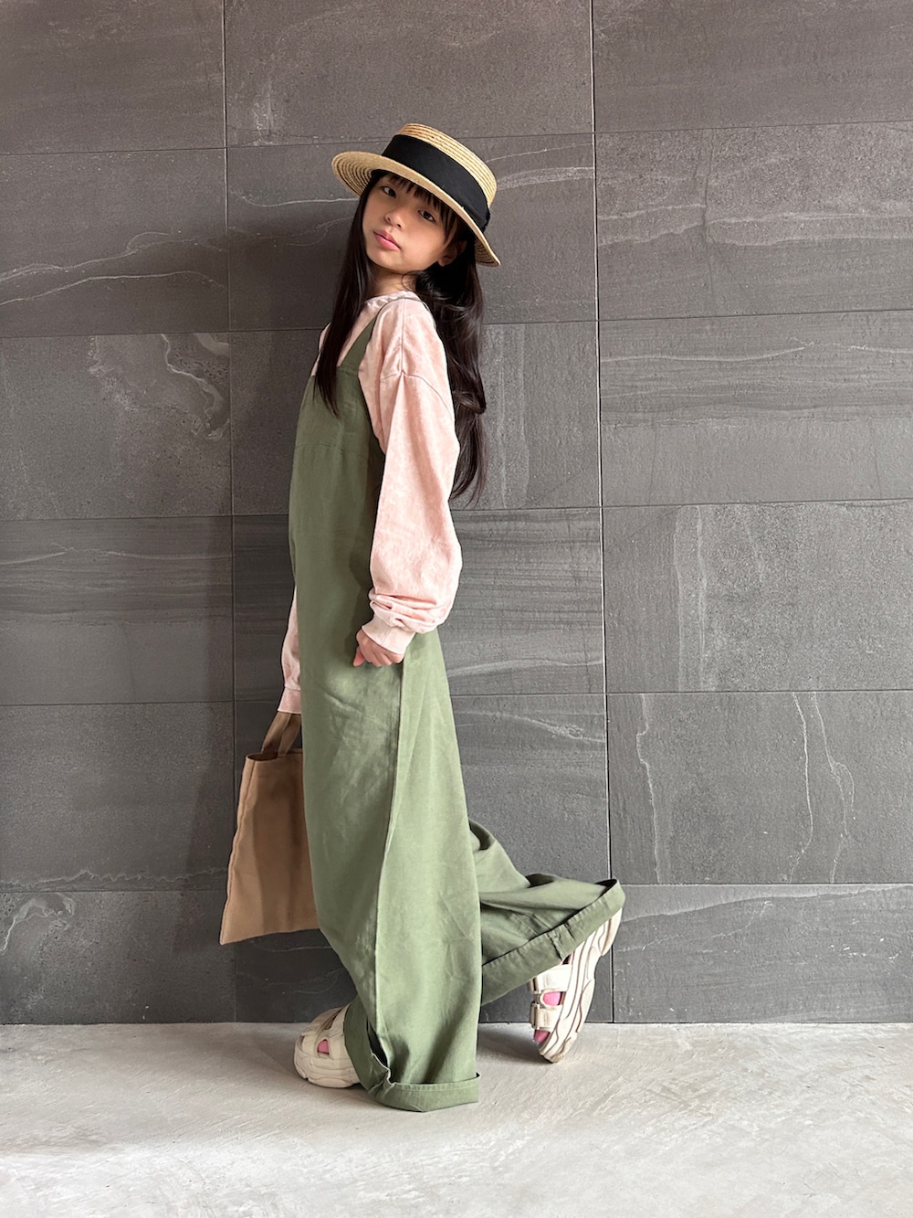 ピンク系のTシャツ/カットソー、グリーン系のサロペット/オーバーオール、ベージュ系のトートバッグを着用したキッズの冬コーディネートの2枚目の写真