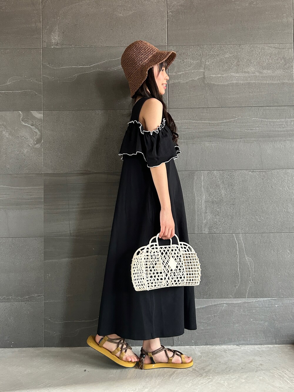 ブラック系のワンピース、オレンジ系のサンダル、ブラウン系のハットを着用したキッズの夏コーディネートの3枚目の写真