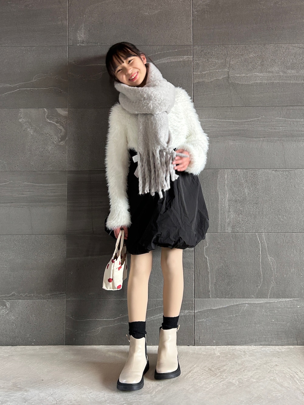 ホワイト系のカーディガン/ボレロ、ブラック系のスカート、ホワイト系のショルダーバッグを着用したキッズの冬コーディネートの2枚目の写真