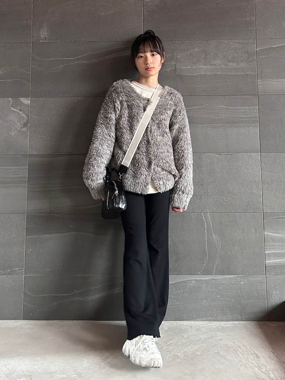 ブラウン系のカーディガン/ボレロ、ベージュ系のTシャツ/カットソー、ブラック系のショルダーバッグを着用したキッズの冬コーディネートの2枚目の写真