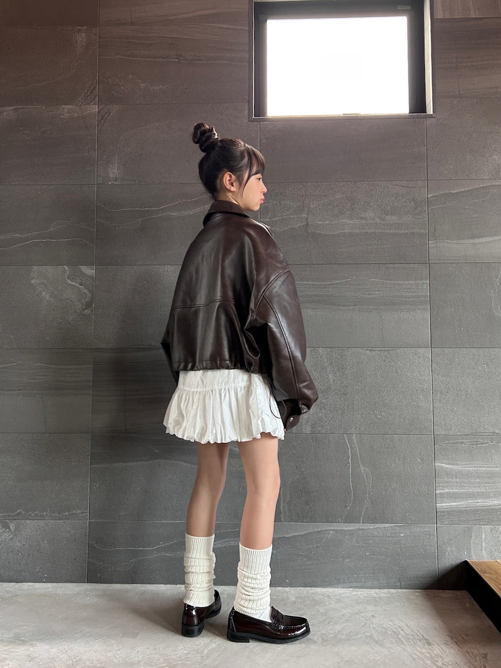 ブラウン系のブルゾン、ホワイト系のスカート、ベージュ系のTシャツ/カットソーを着用したキッズの冬コーディネートの4枚目の写真