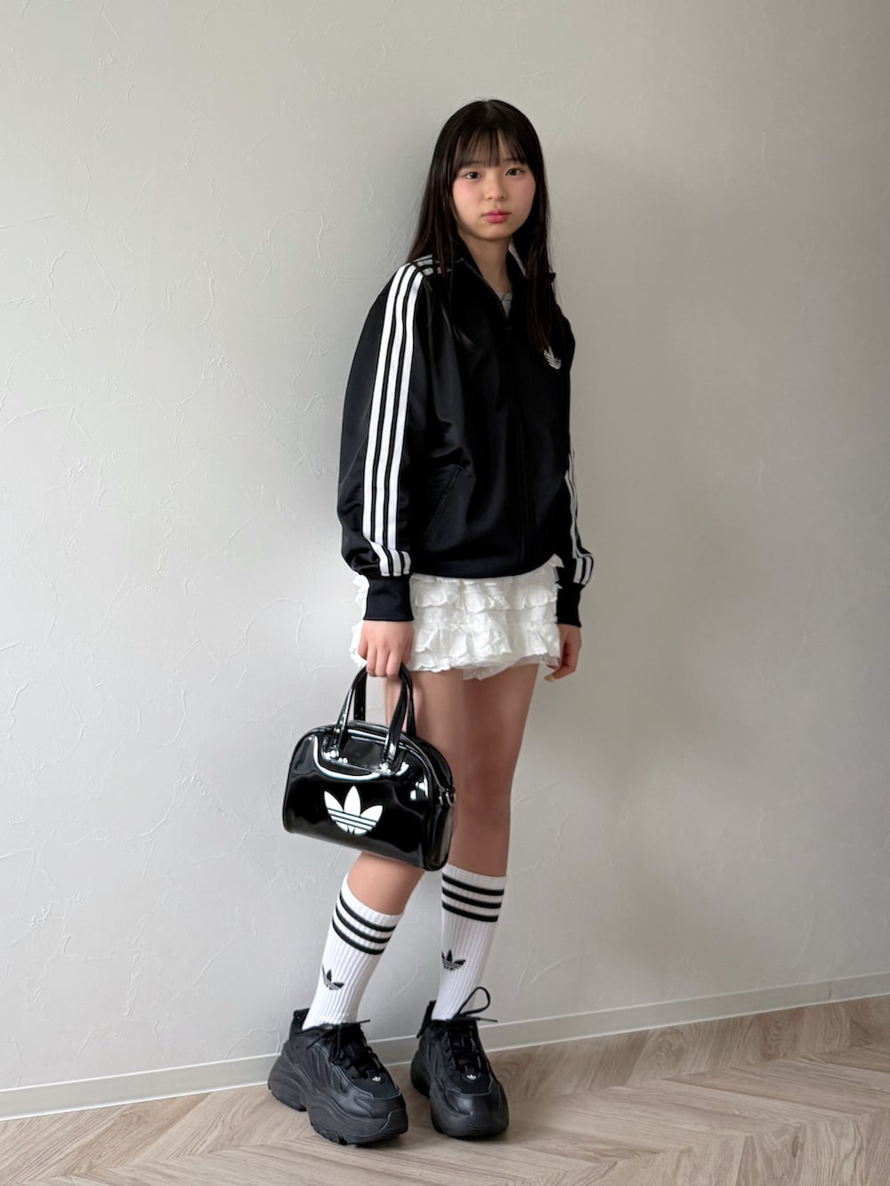 ブラック系のジャージ、ブラック系のショルダーバッグ、ブラック系のスニーカーを着用したキッズの春コーディネートの2枚目の写真