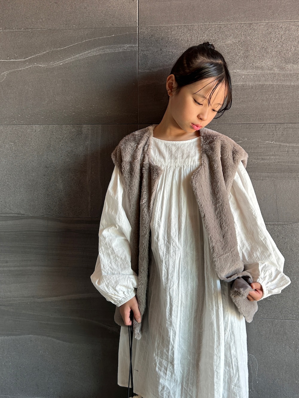 グレー系のベスト、ブラウン系のスウェットパンツ、ホワイト系のワンピースを着用したキッズの秋コーディネートの5枚目の写真