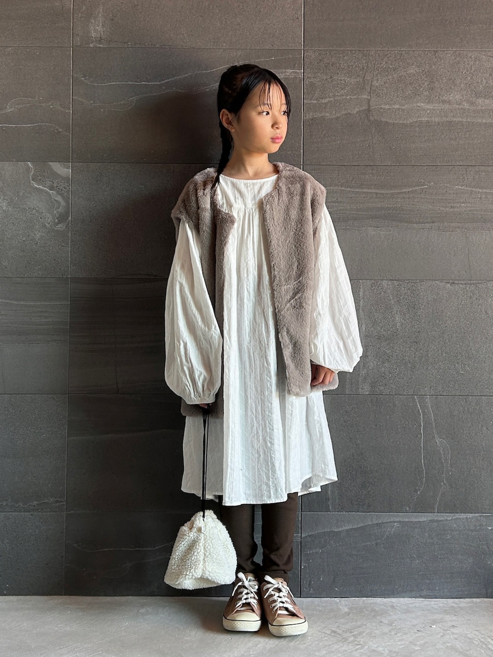 グレー系のベスト、ブラウン系のスウェットパンツ、ホワイト系のワンピースを着用したキッズの秋コーディネートの3枚目の写真