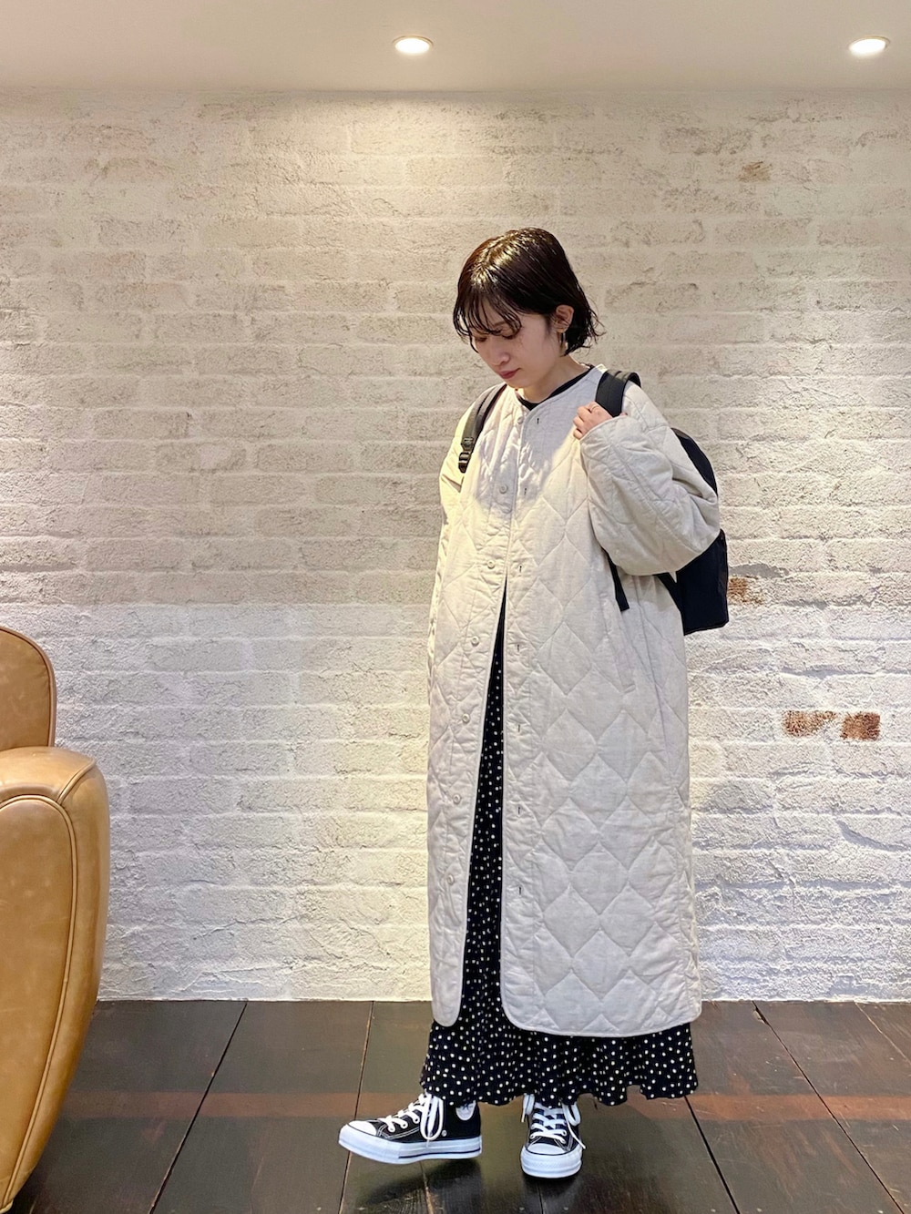 ブラック系のスニーカー、ブラック系のスカート、ベージュ系のその他アウターを着用したレディースの冬コーディネートの2枚目の写真