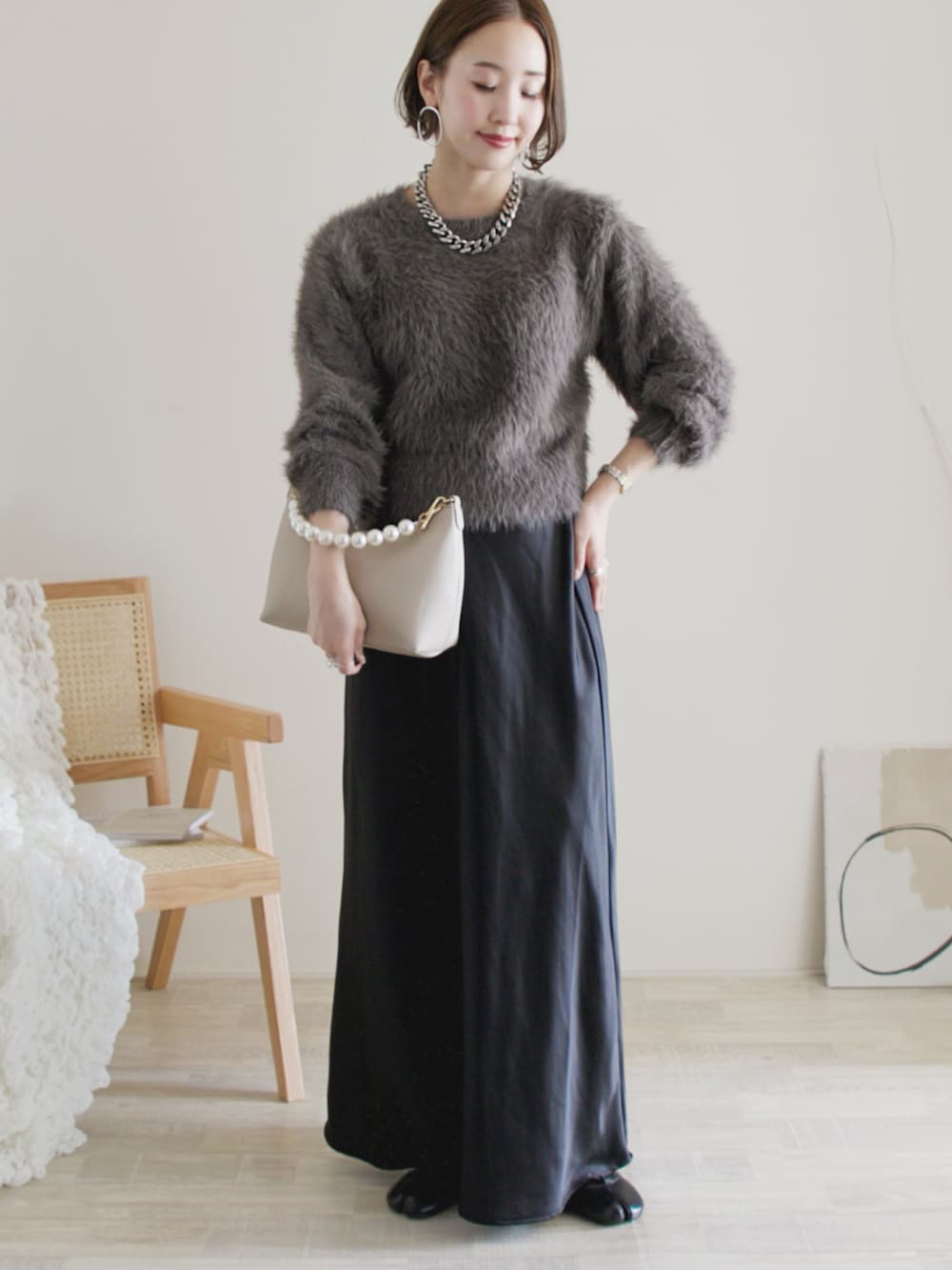 グレー系のニット/セーター、ブラック系のスカート、ブラック系のバレエシューズを着用したレディースの秋コーディネートの2枚目の写真