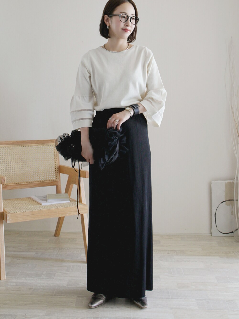ブラック系のスカート、ホワイト系のニット/セーター、ブラック系のショルダーバッグを着用したレディースの秋コーディネートの2枚目の写真