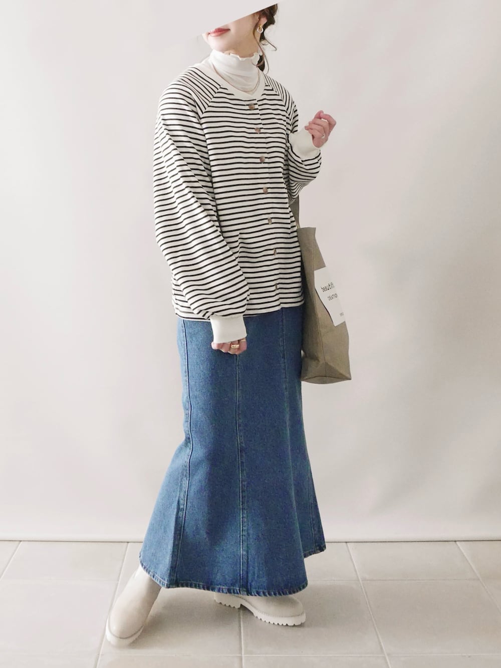 ホワイト系のトップス、ブルー系のデニムスカート、ベージュ系のブーツを着用したレディースの冬コーディネートの2枚目の写真