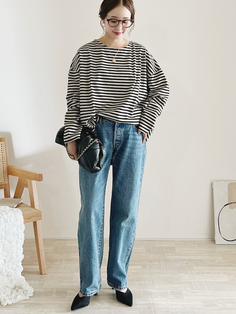 ベージュ系のTシャツ/カットソー、ブラック系のクラッチバッグ、ブルー系のデニムパンツを着用したレディースの秋コーディネートの2枚目の写真