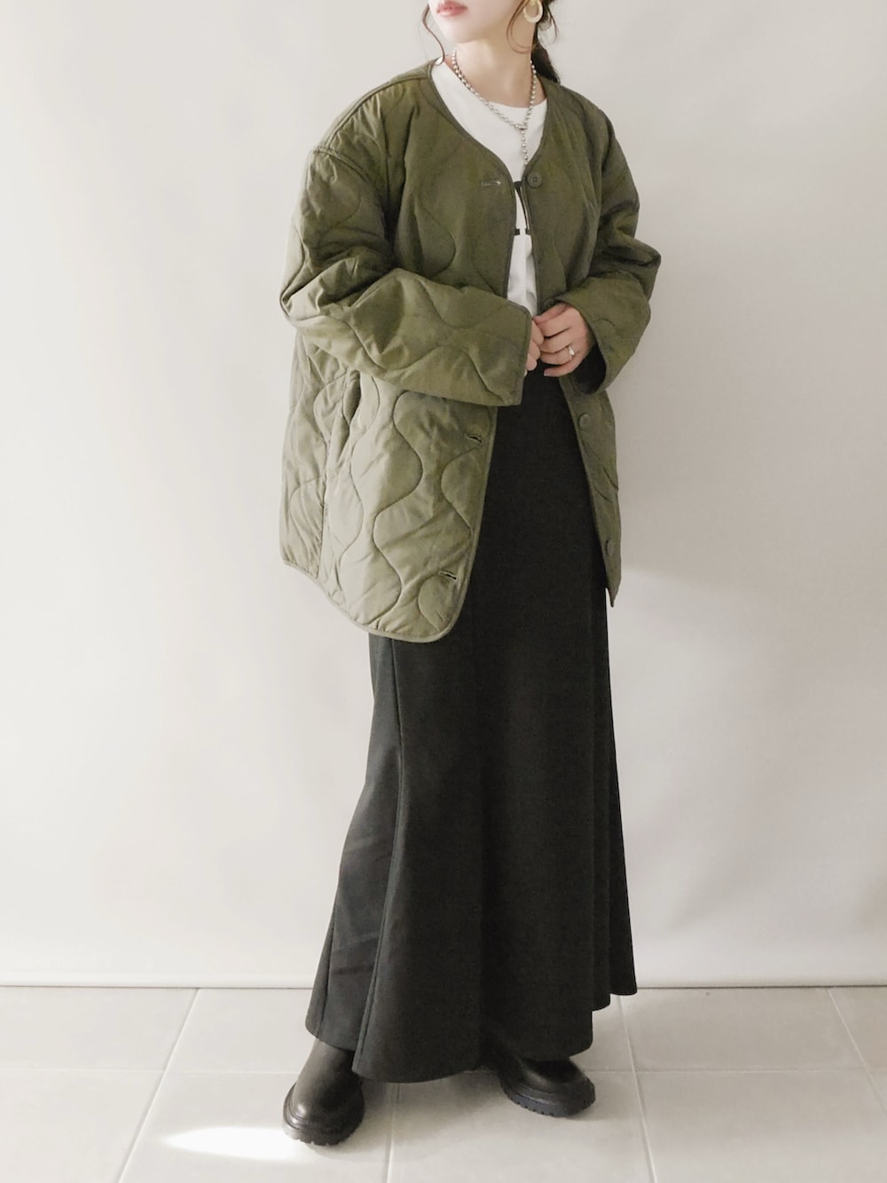 グリーン系のジャケット/アウター、ホワイト系のトップス、ブラック系のスカートを着用したレディースの秋コーディネートの2枚目の写真