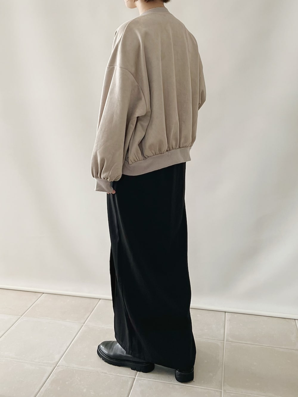 ブラック系のワンピース、ベージュ系のスタジャン、ホワイト系のバッグを着用したレディースの秋コーディネートの3枚目の写真