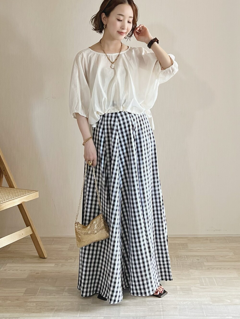 ホワイト系のシャツ/ブラウス、ブラック系のスカート、ゴールド系のショルダーバッグを着用したレディースの夏コーディネートの2枚目の写真