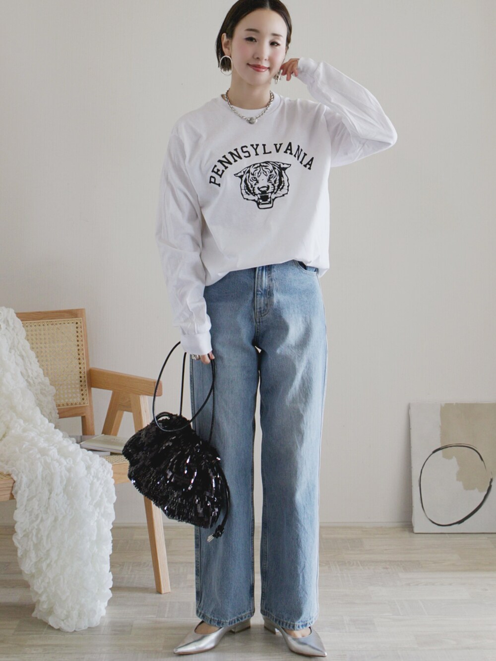 ホワイト系のTシャツ/カットソー、ブルー系のデニムパンツ、ブラック系のクラッチバッグを着用したレディースの春コーディネートの2枚目の写真