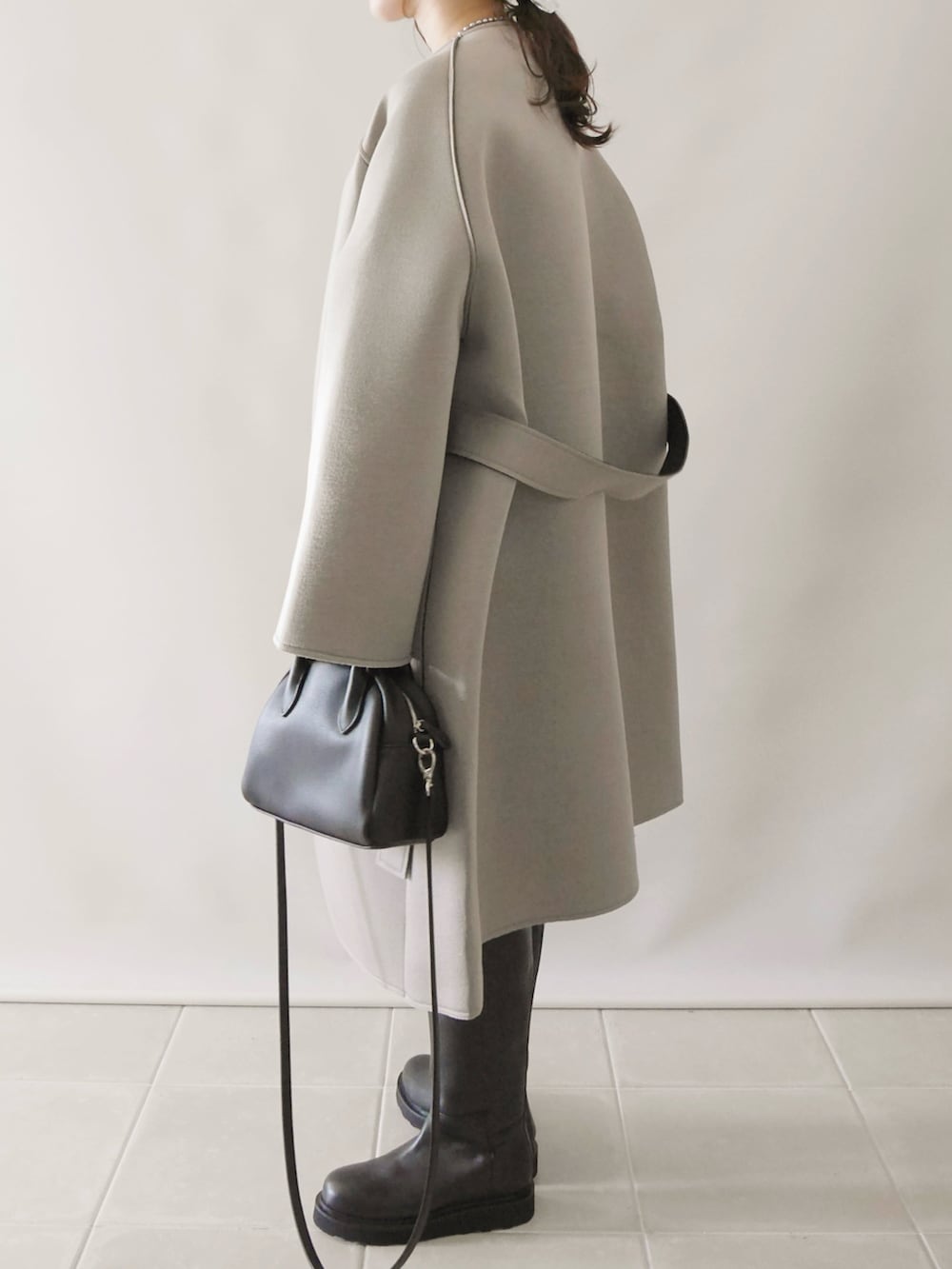 グレー系のノーカラーコート、ホワイト系のTシャツ/カットソー、ブラック系のボストンバッグを着用したレディースの秋コーディネートの2枚目の写真