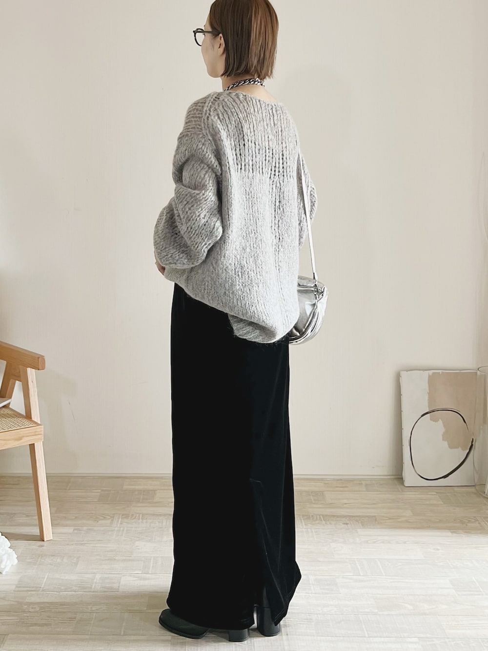 グレー系のニット/セーター、ブラック系のスカート、シルバー系のハンドバッグを着用したレディースの秋コーディネートの2枚目の写真