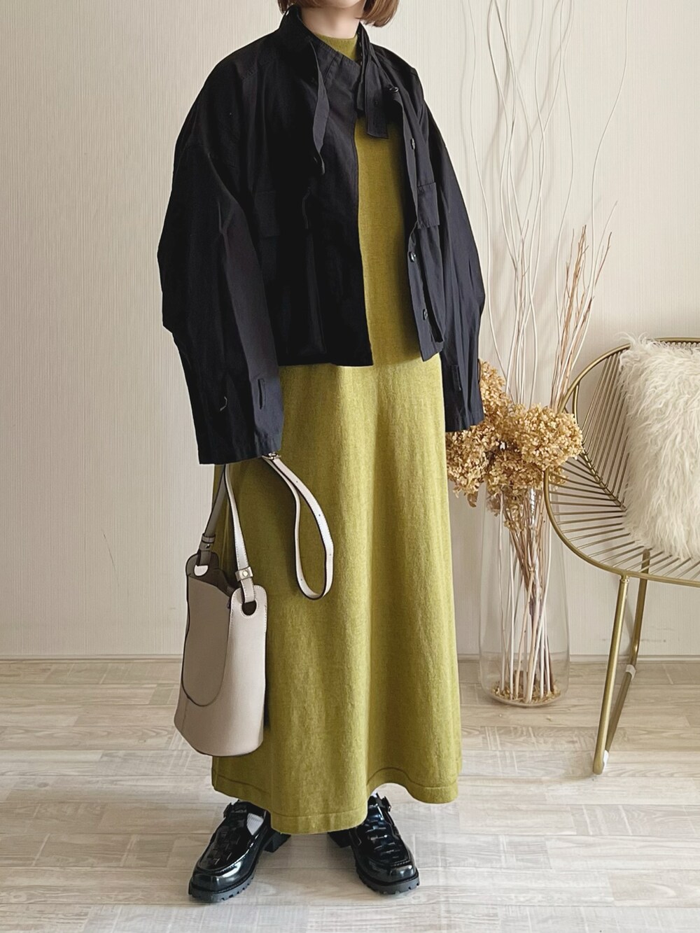 グリーン系のワンピース、ブラック系のブルゾン、ベージュ系のトートバッグを着用したレディースの秋コーディネートの2枚目の写真