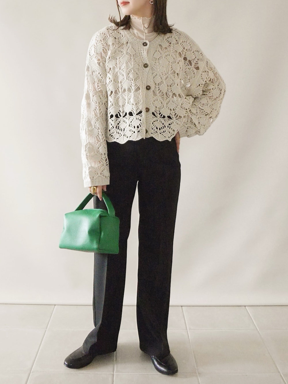 ホワイト系のカーディガン/ボレロ、ブラック系のパンツ、グリーン系のハンドバッグを着用したレディースの春コーディネートの2枚目の写真
