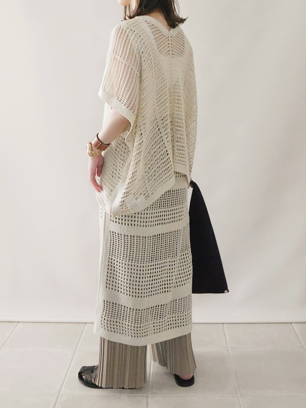 ベージュ系のニット/セーター、ベージュ系のワンピース、ブラック系のサンダルを着用したレディースの春コーディネートの3枚目の写真