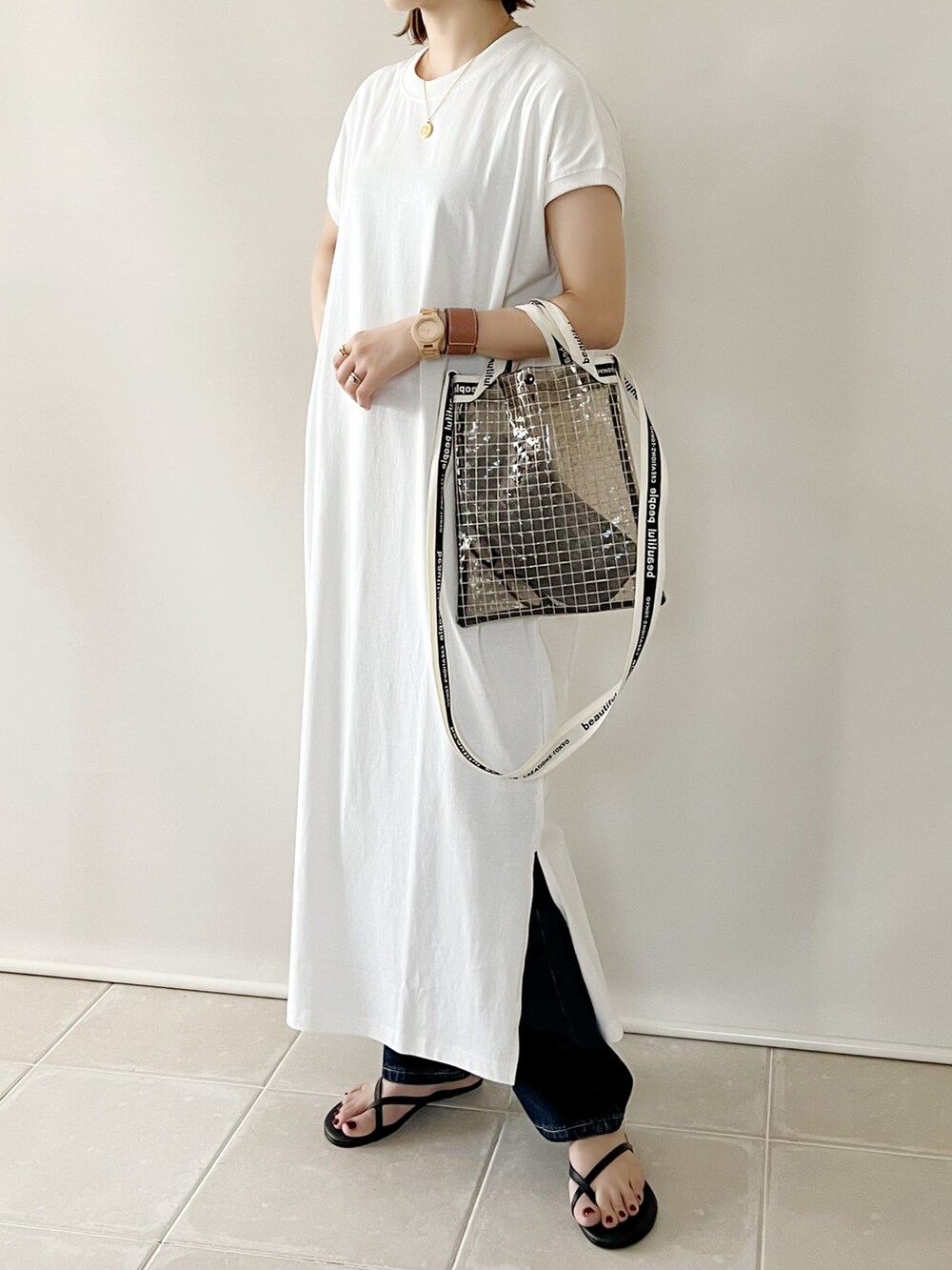 ホワイト系のワンピース、ブラック系のショルダーバッグ、ブルー系のデニムパンツを着用したレディースの夏コーディネートの4枚目の写真