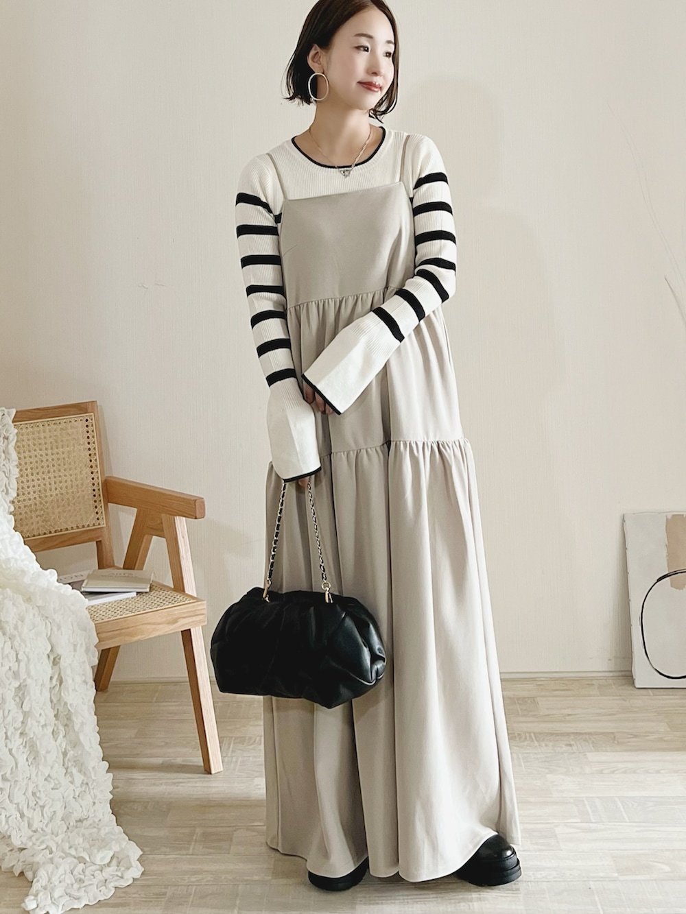 ホワイト系のニット/セーター、ベージュ系のジャンパースカート、ブラック系のブーツを着用したレディースの秋コーディネートの2枚目の写真