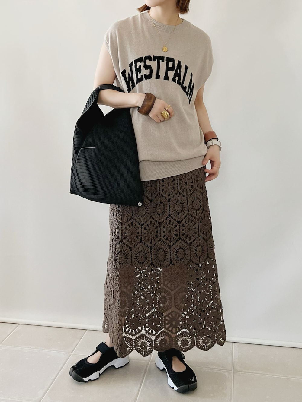 ベージュ系のTシャツ/カットソー、ブラウン系のスカート、ブラック系のハンドバッグを着用したレディースの夏コーディネートの2枚目の写真