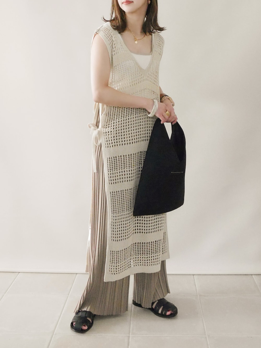 ベージュ系のニット/セーター、ベージュ系のワンピース、ブラック系のサンダルを着用したレディースの春コーディネートの4枚目の写真