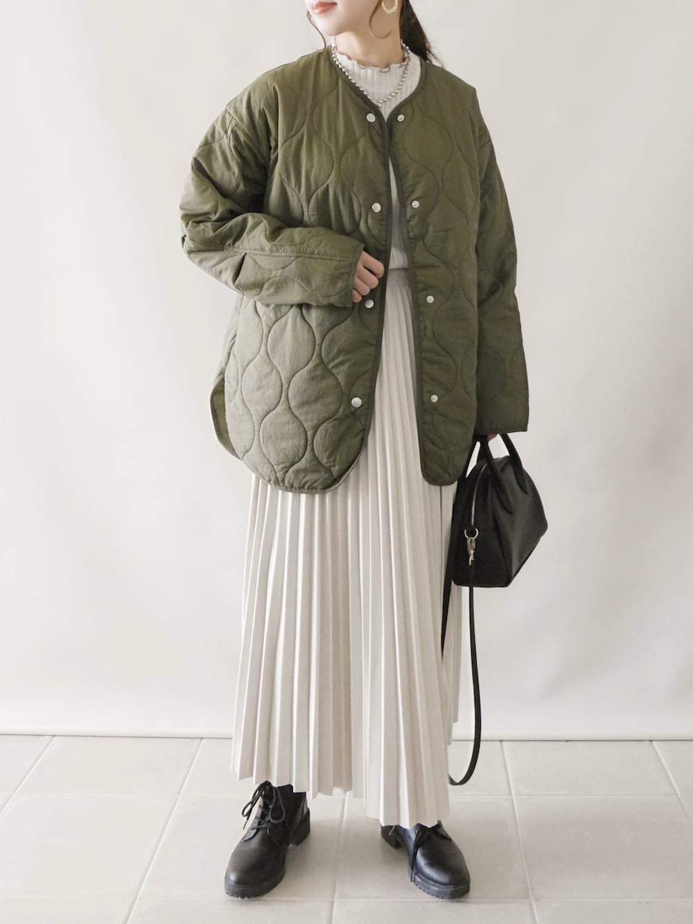 グリーン系のノーカラーコート、ブラック系のワンピース/ドレス、イエロー系のトートバッグを着用したレディースの秋コーディネートの3枚目の写真