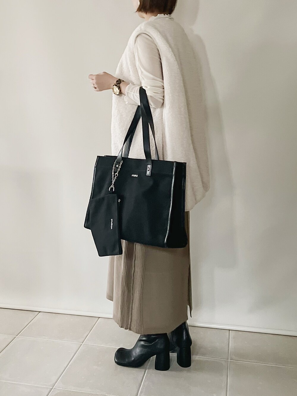 ブラック系のトートバッグ、ホワイト系のベスト、ベージュ系のワンピース/ドレスを着用したレディースの秋コーディネートの2枚目の写真