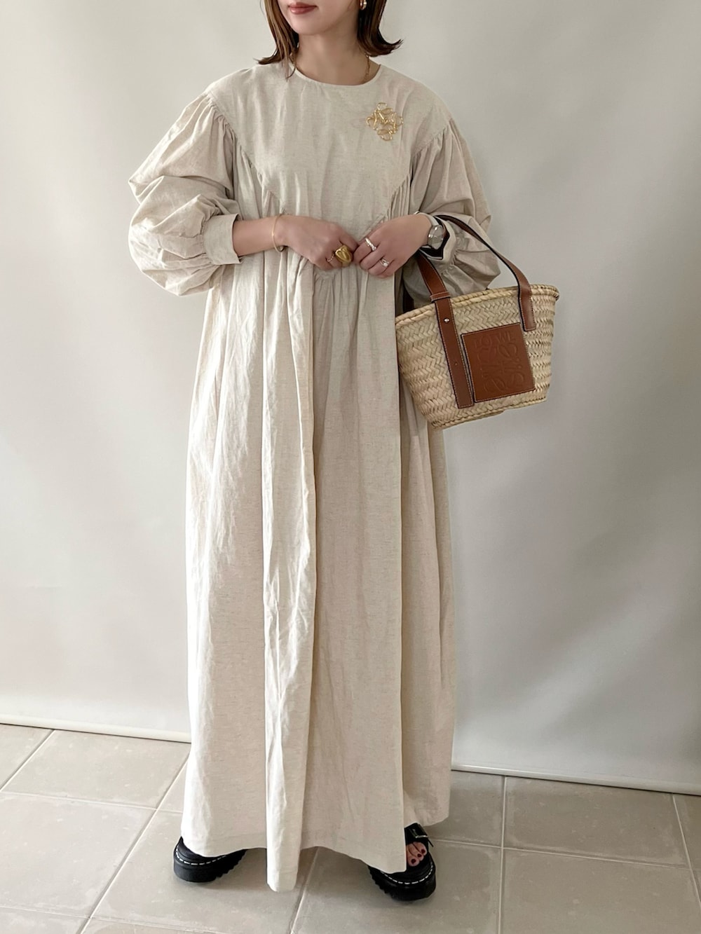 ベージュ系のワンピース、ベージュ系のかごバッグ、ブラック系のサンダルを着用したレディースの春コーディネートの3枚目の写真