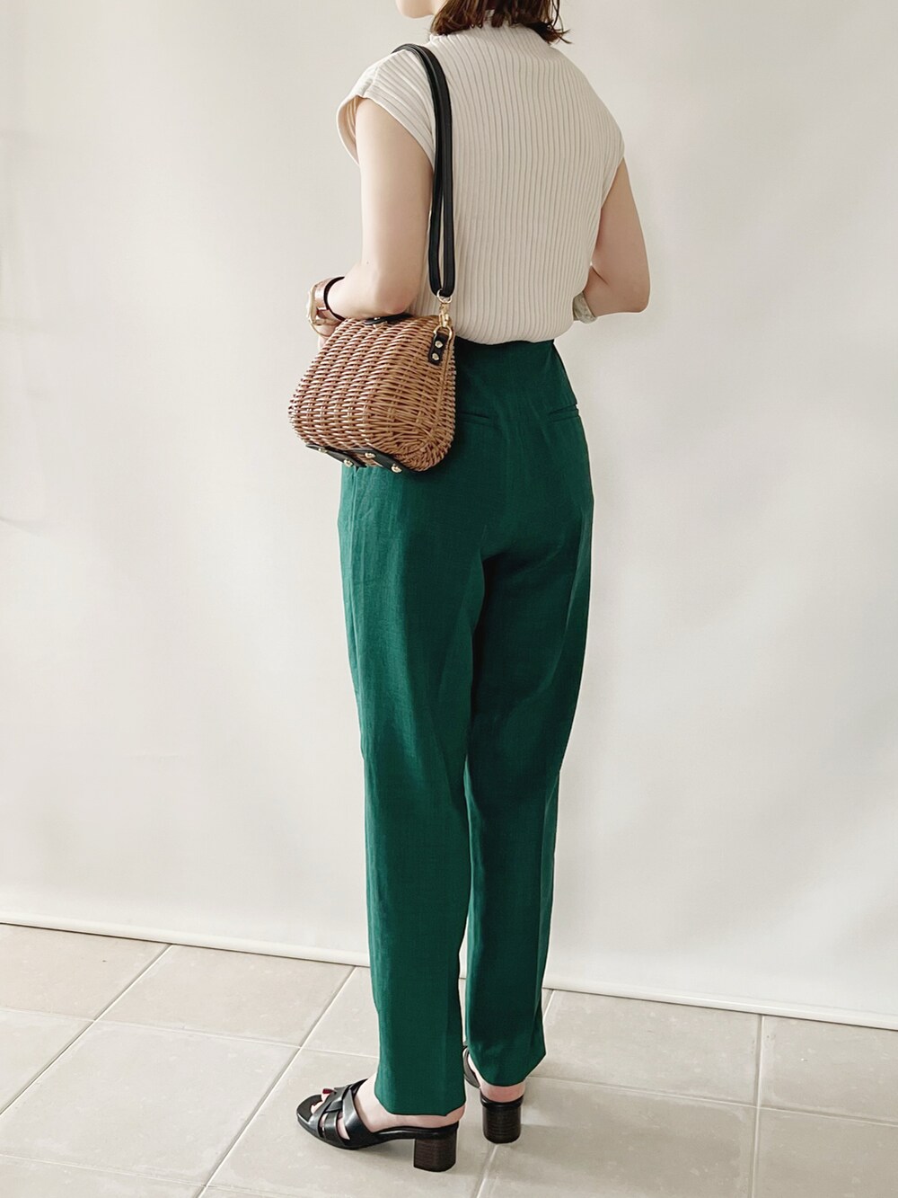 グリーン系のその他パンツ、ホワイト系のニット/セーター、ブラウン系のかごバッグを着用したレディースの春コーディネートの3枚目の写真