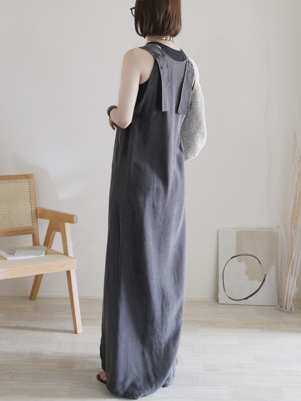 グレー系のワンピース、ブラック系のトップス、ブラック系のサンダルを着用したレディースの夏コーディネートの3枚目の写真