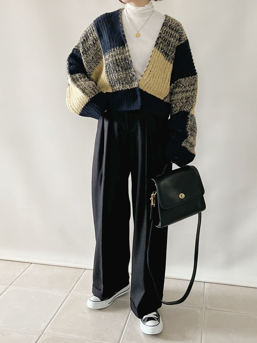 ブルー系のカーディガン/ボレロ、ブラック系のパンツ、ブラック系のバッグを着用したレディースの秋コーディネートの2枚目の写真