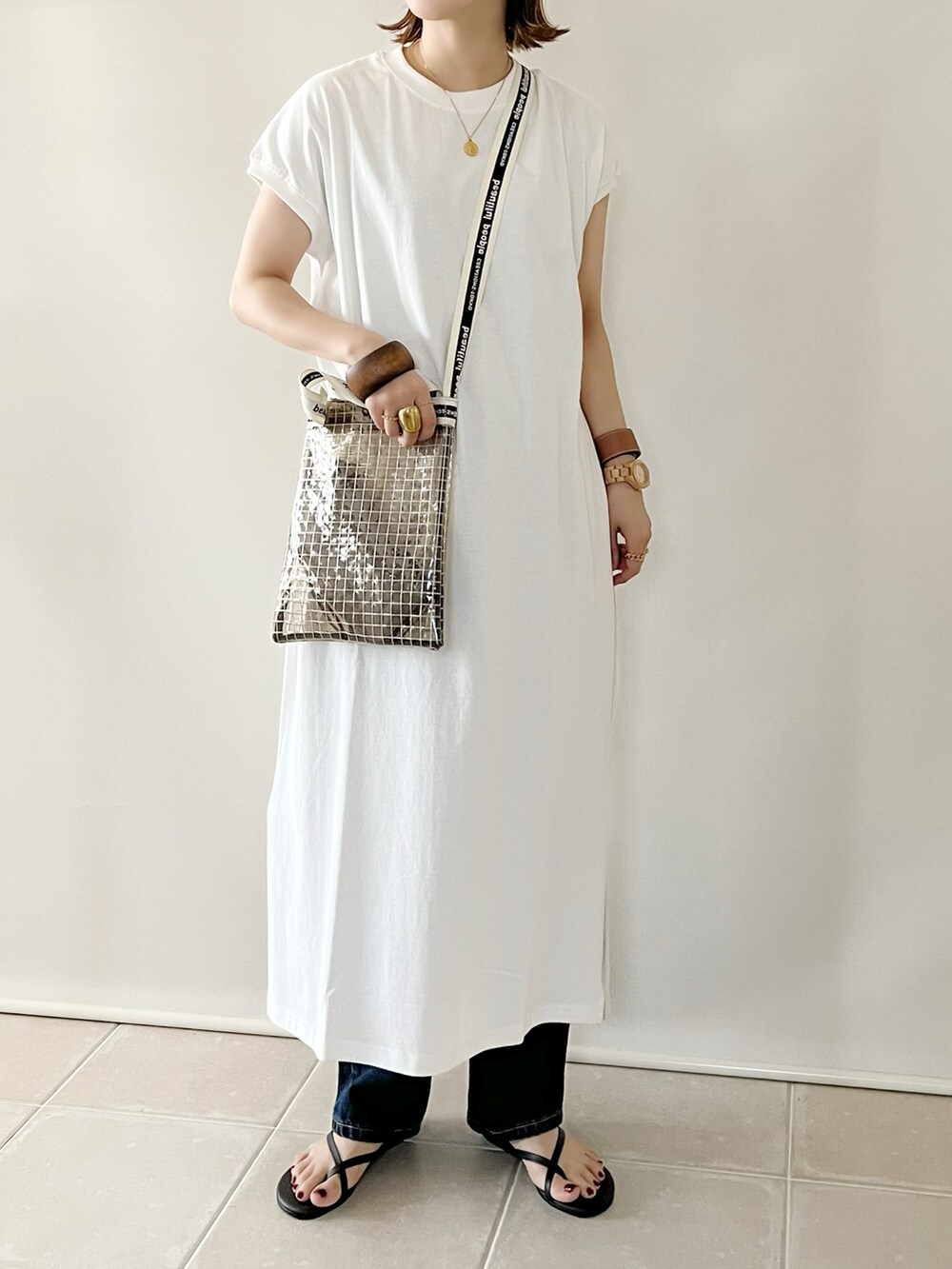 ホワイト系のワンピース、ブラック系のショルダーバッグ、ブルー系のデニムパンツを着用したレディースの夏コーディネートの3枚目の写真