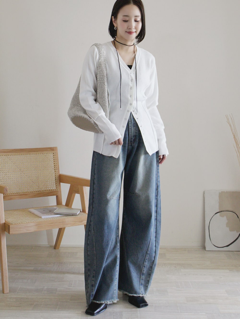 ブルー系のデニムパンツ、ホワイト系のカーディガン/ボレロ、シルバー系のショルダーバッグを着用したレディースの秋コーディネートの2枚目の写真