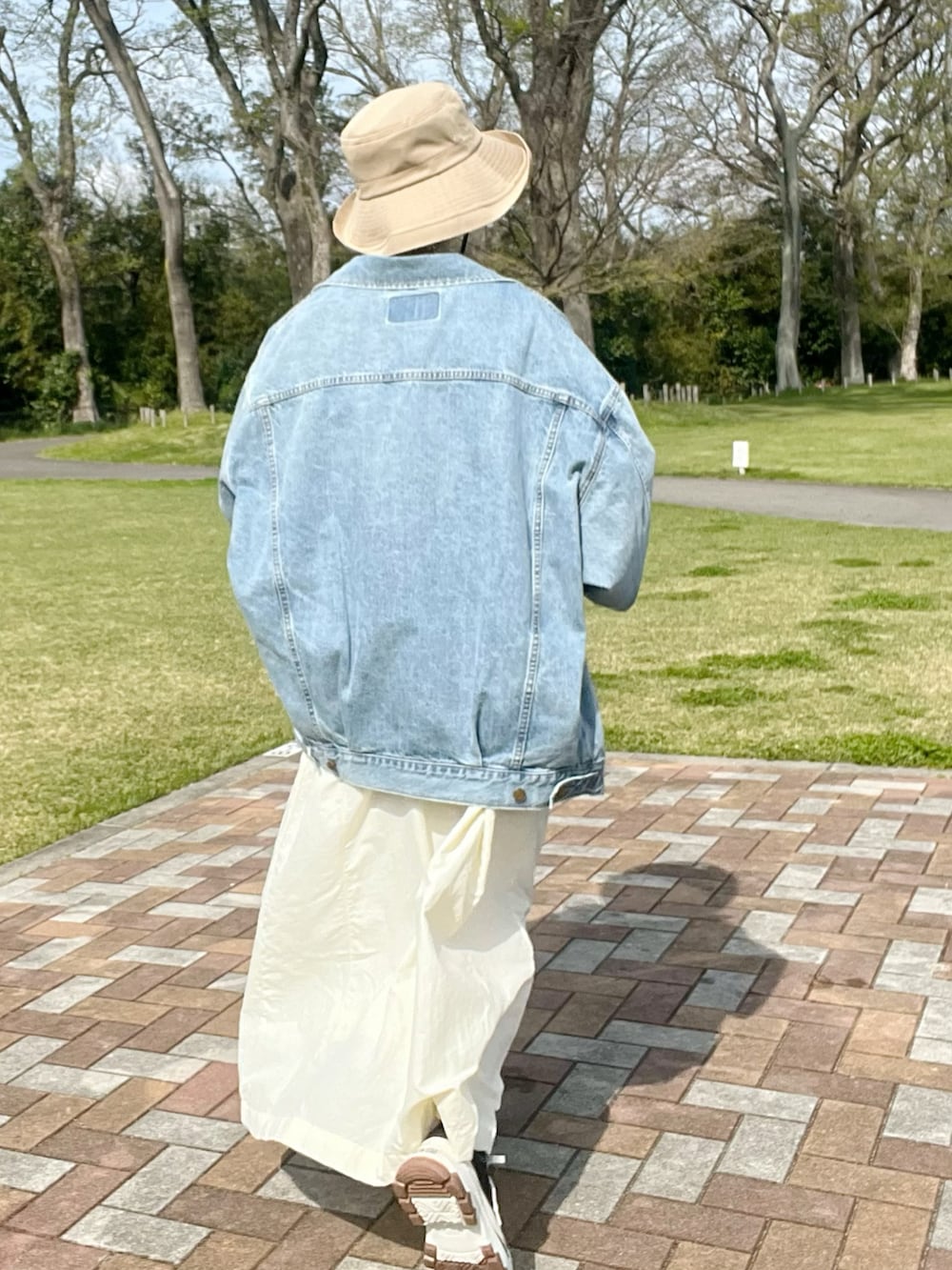 ブルー系のデニムジャケット、ベージュ系のワンピース、ブラック系のスニーカーを着用したレディースの春コーディネートの2枚目の写真